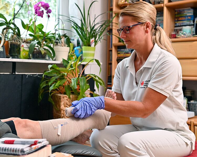 Eine Pflegerin verbindet ein Bein.